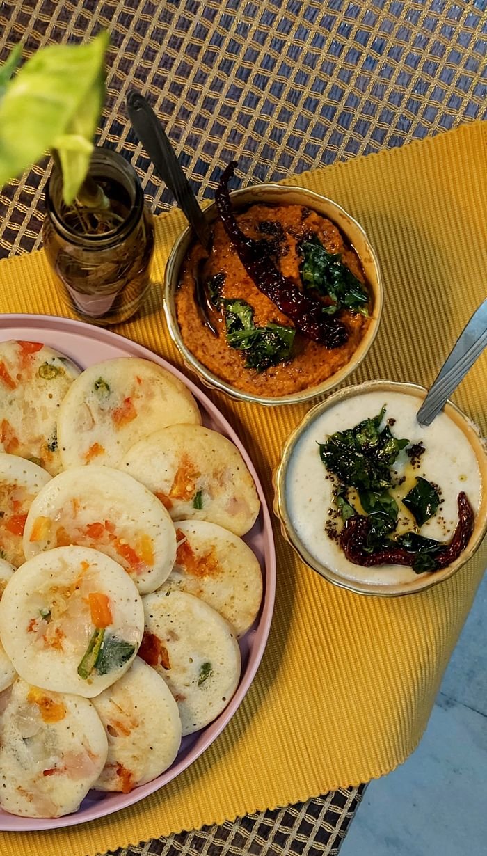 Tasty uttapam served with spicy chutney and yogurt sauce from a high angle.
